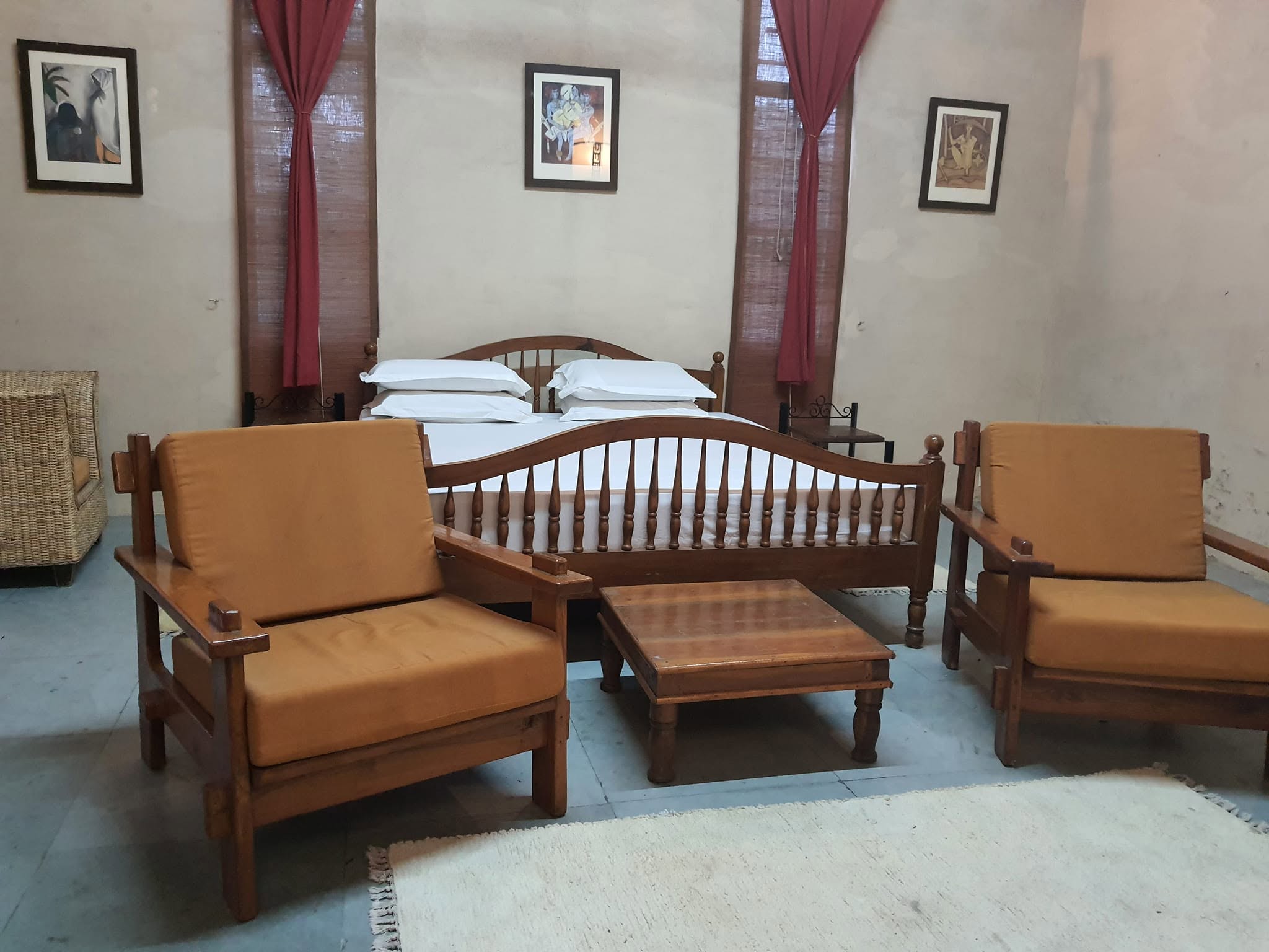 Bedroom with a sitting area beside tall windows