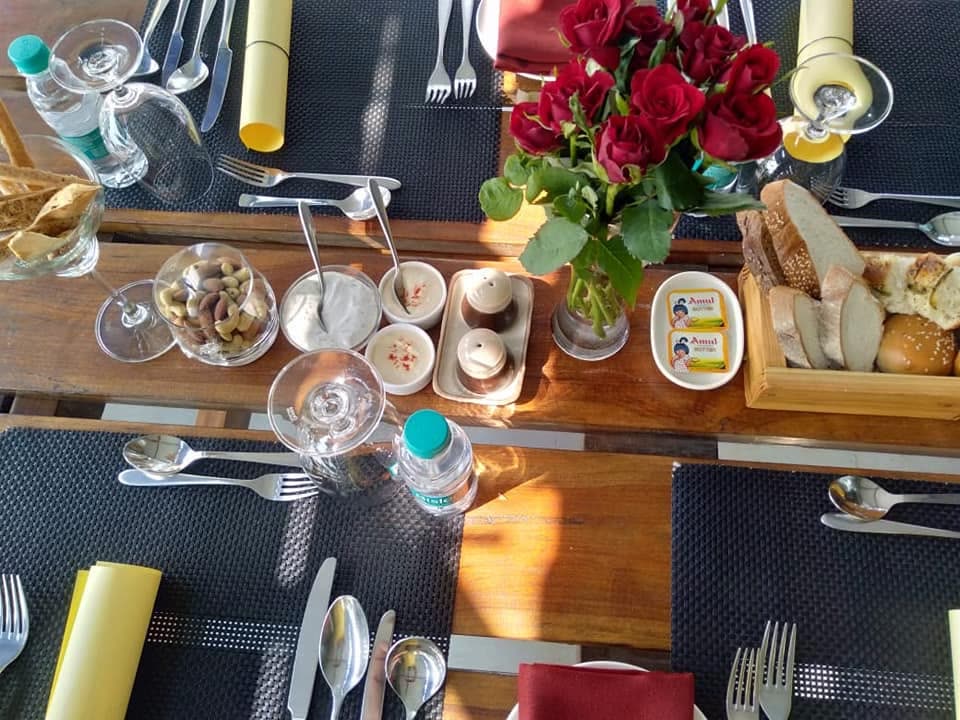 Breakfast table laid with cutlery, breads and red roses