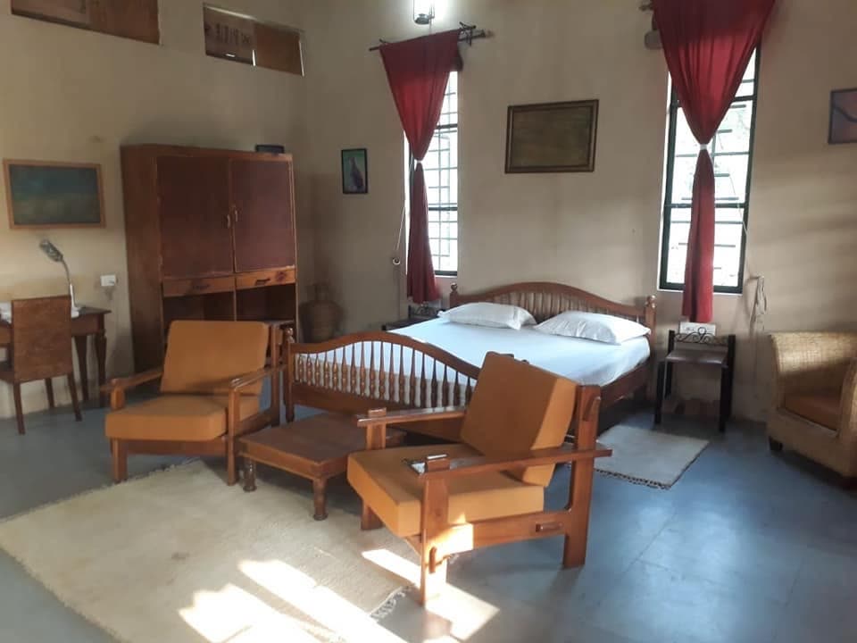 Sunlit guest room with wooden lounge chairs and a writing cupboard