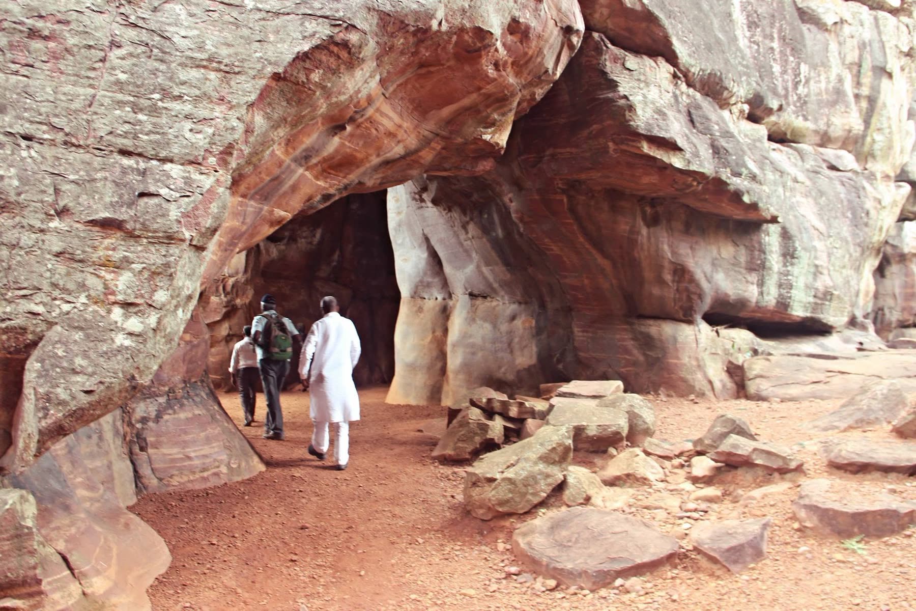 Visitors exploring a sandstone rock shelter at Bhimbetka