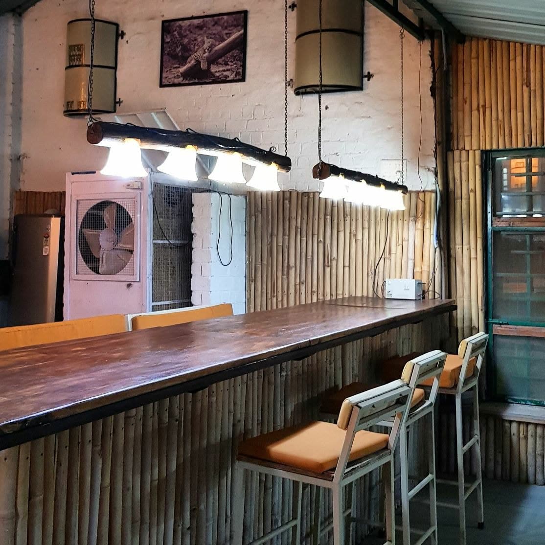 Long wooden bar counter with bamboo trim and pendant lamps