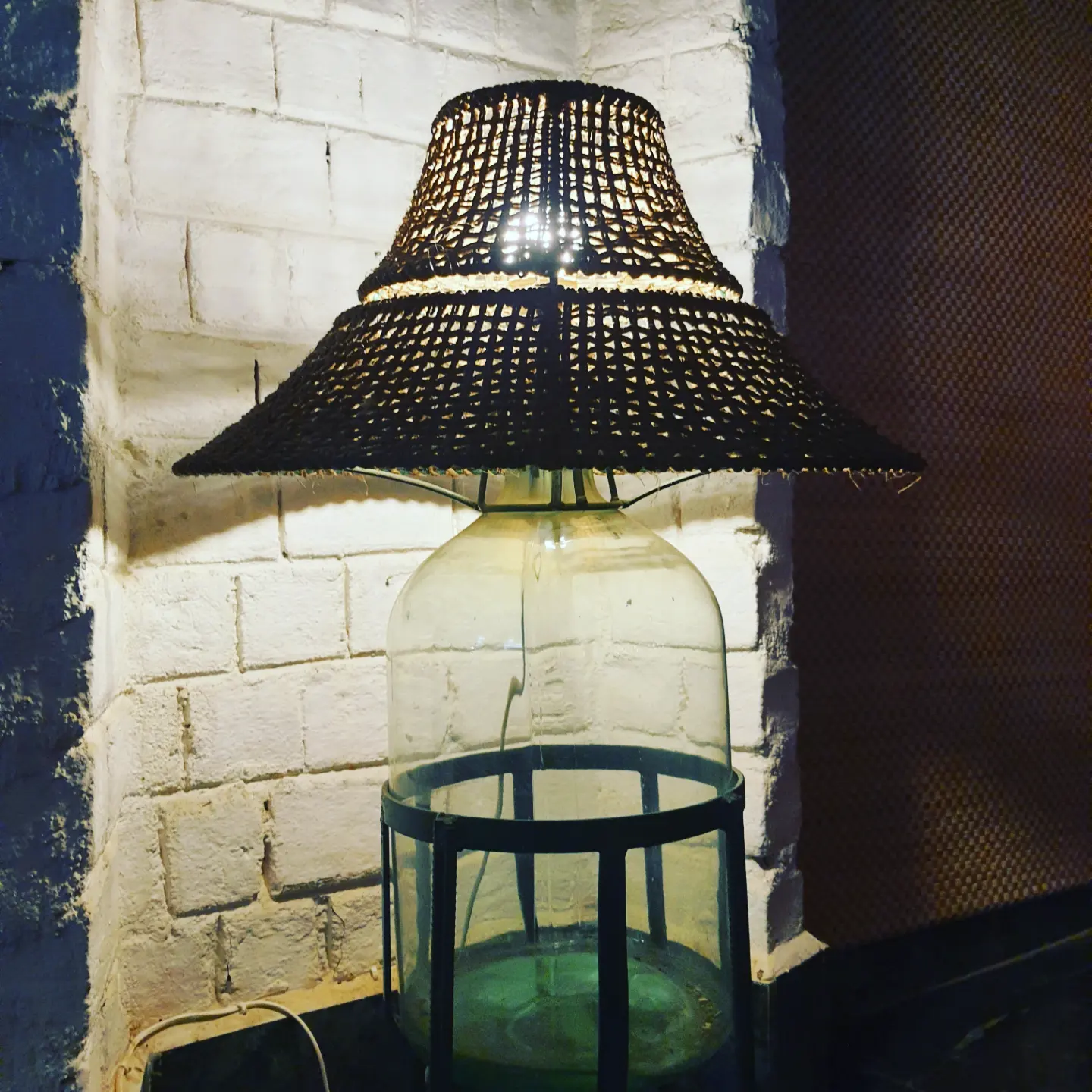 Woven lamp shade against a whitewashed stone wall